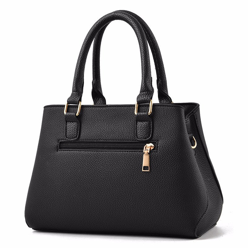 Henkeltasche mit Flechtprägung und Pompon-Anhänger