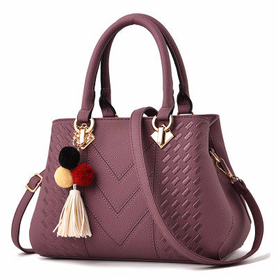 Henkeltasche mit Flechtprägung und Pompon-Anhänger