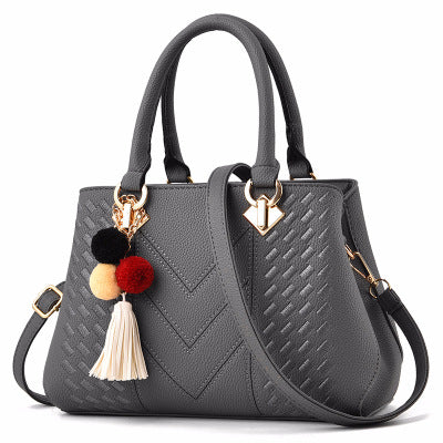 Henkeltasche mit Flechtprägung und Pompon-Anhänger