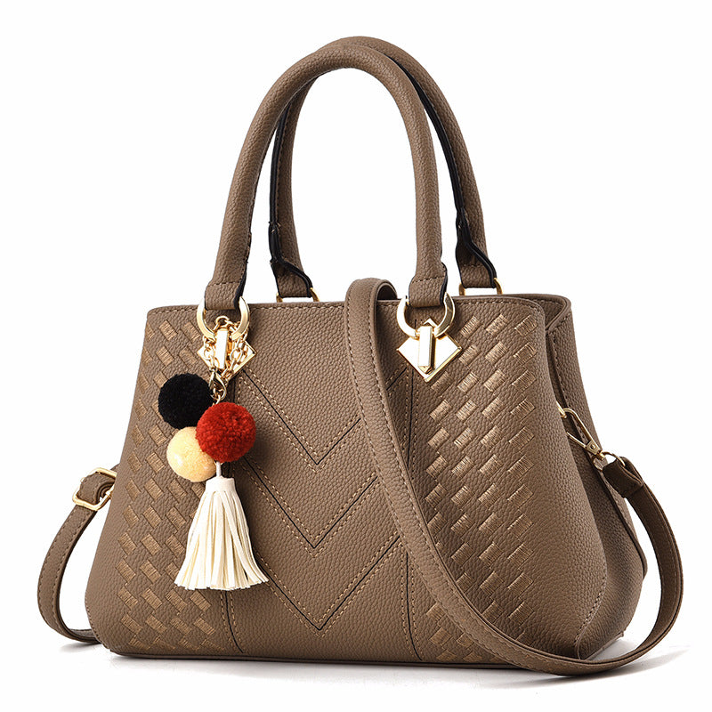 Henkeltasche mit Flechtprägung und Pompon-Anhänger