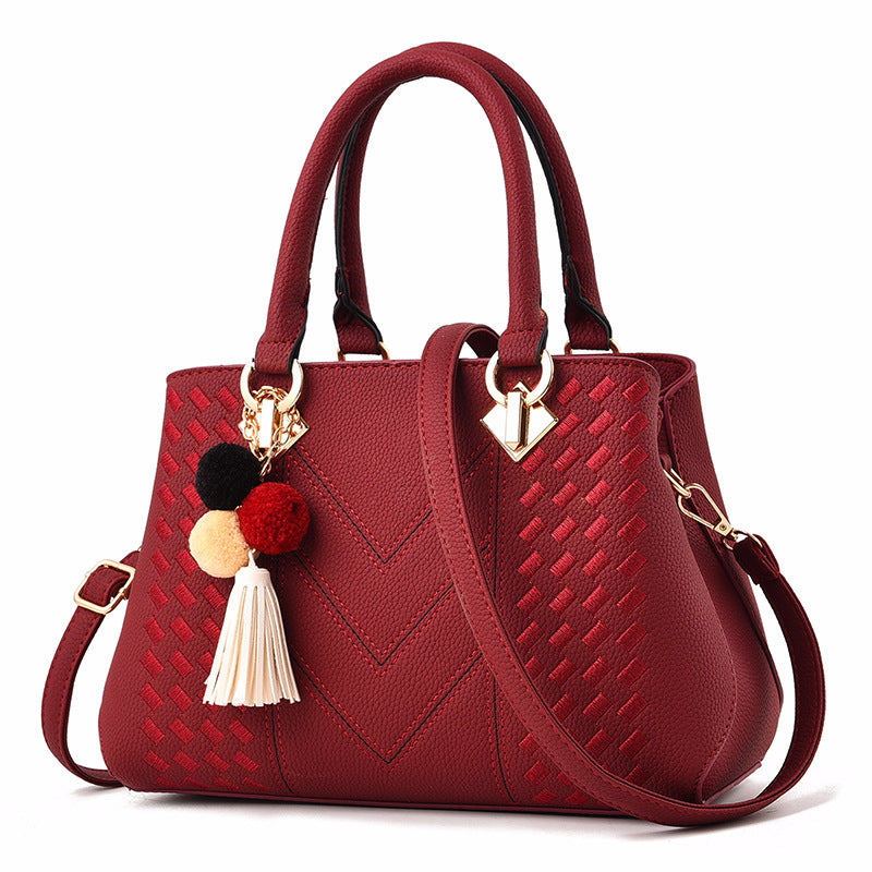 Henkeltasche mit Flechtprägung und Pompon-Anhänger