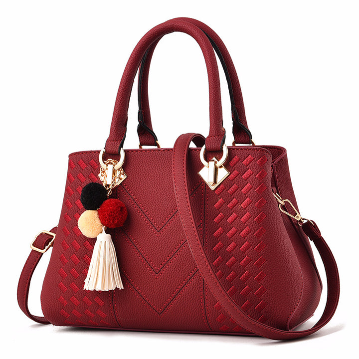 Henkeltasche mit Flechtprägung und Pompon-Anhänger